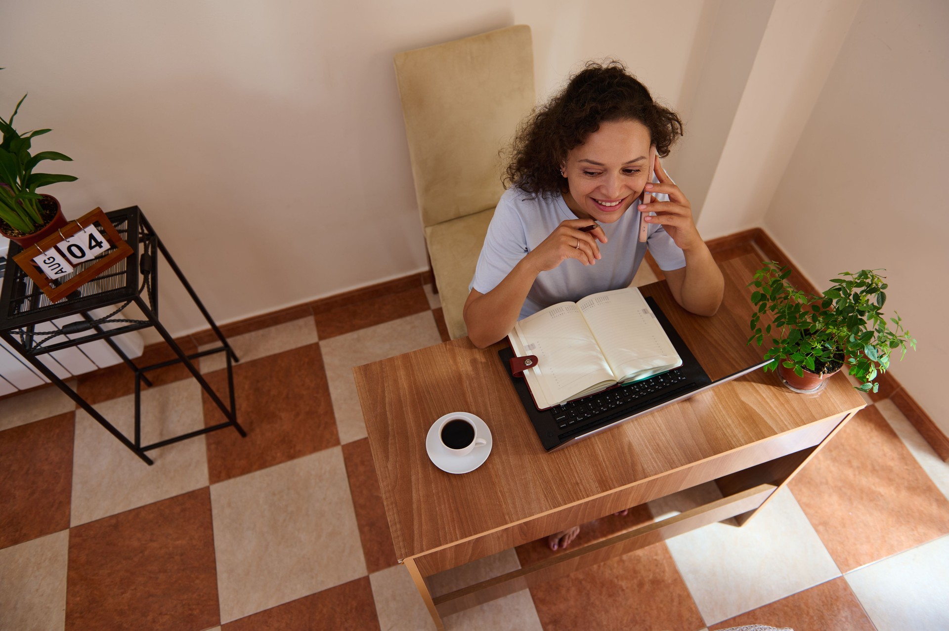 Trabalho remoto em casa com uma mulher falando ao telefone em uma mesa