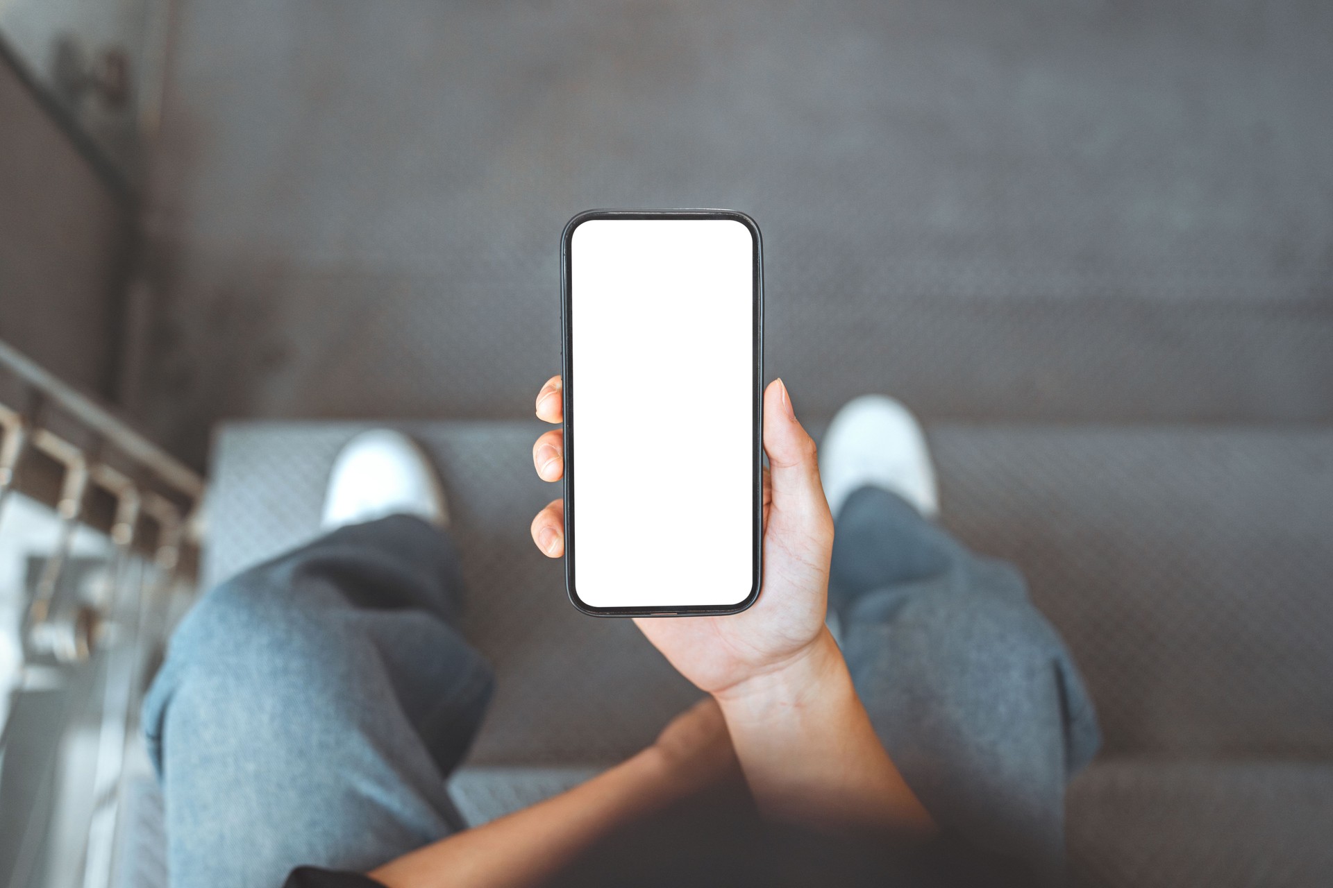 Feche acima - mãos do homem usando o mockup branco da tela branca do telefone celular, espaço vazio do fundo para anunciar, tecnologia